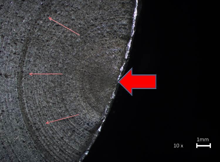 Figura 4 Aspecto macrográfico mostrando o início da formação da trinca e a partir dele, a propagação das beach marks. As setas indicam o ponto inicial e o sentido de propagação da trinca.