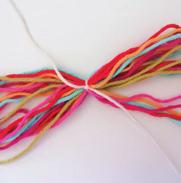 Corte um pedaço do fio da cor base com cerca de 50cm e prenda-o em torno do bloco de fios que