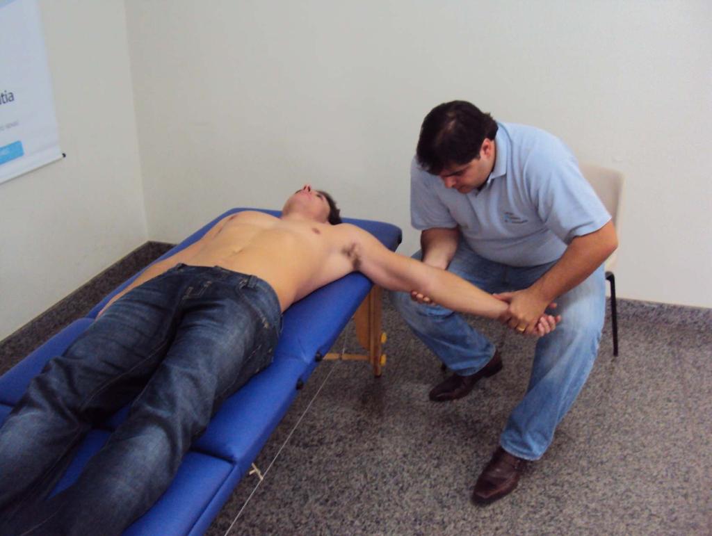 5.3 - Técnica de liberação do músculo braquial Paciente em decúbito dorsal. Osteopata sentado ao lado do paciente posicionando o membro superior em 90 graus de abdução e apoiandoo sobre a coxa.