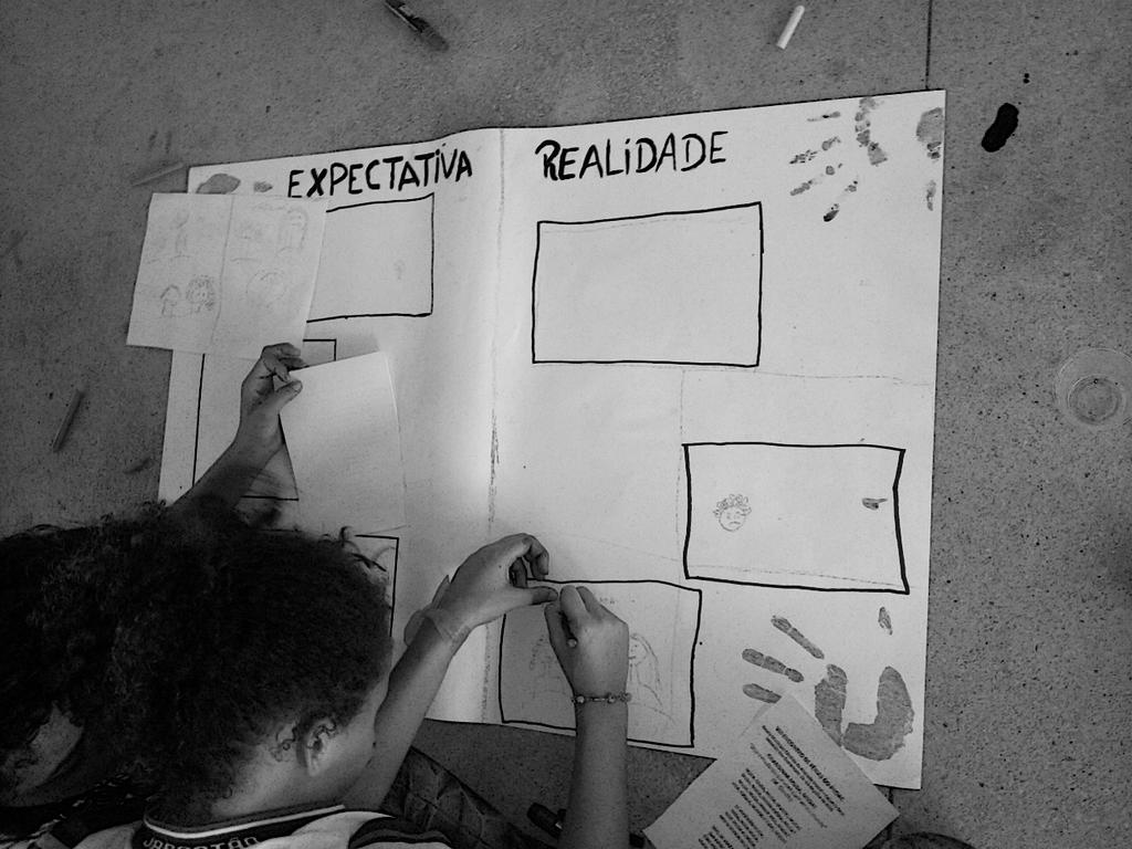 Sonhos em tons de cinza: as cores que estão fora do cartaz da educação Fotografia em preto e branco, em formato paisagem, do ombro para cima, de uma menina negra que está de costas.