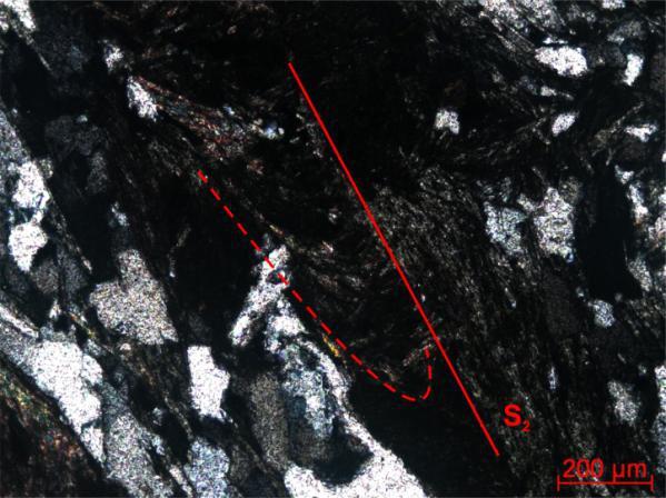 A análise microscópica mostrou ainda a foliação/clivagem ardosiana ou filítica pretérita S 1, transposta pela foliação S 2, identificada em relictos de dobras ou crenulações na forma de arcos