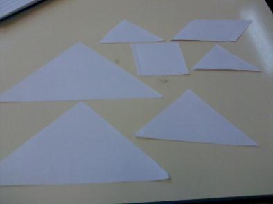 Nesta aula começamos por cortar uma folha A4 de forma a construirmos o nosso próprio tangran, sendo que de um triângulo temos de dobrar e cortar para fazer dois iguais e mais pequenos, de um trapézio
