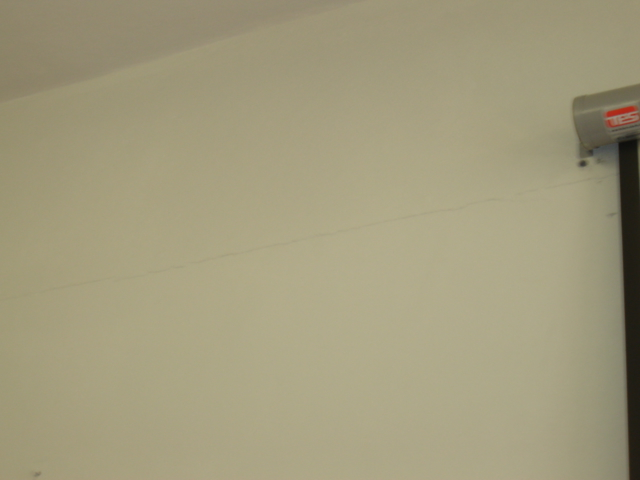 Trincas simples e de junção da viga com a alvenaria em toda a extensão da sala; geralmente trincas desse tipo são causadas pela falta de amarração da parede com algum elemento estrutural (pilar, viga