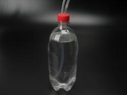 Encaixe uma das tampas já furadas na garrafa PET vazia (garrafa A). Coloque uma das extremidades do tubo 1 nessa garrafa até que ele fique bem próximo do fundo.
