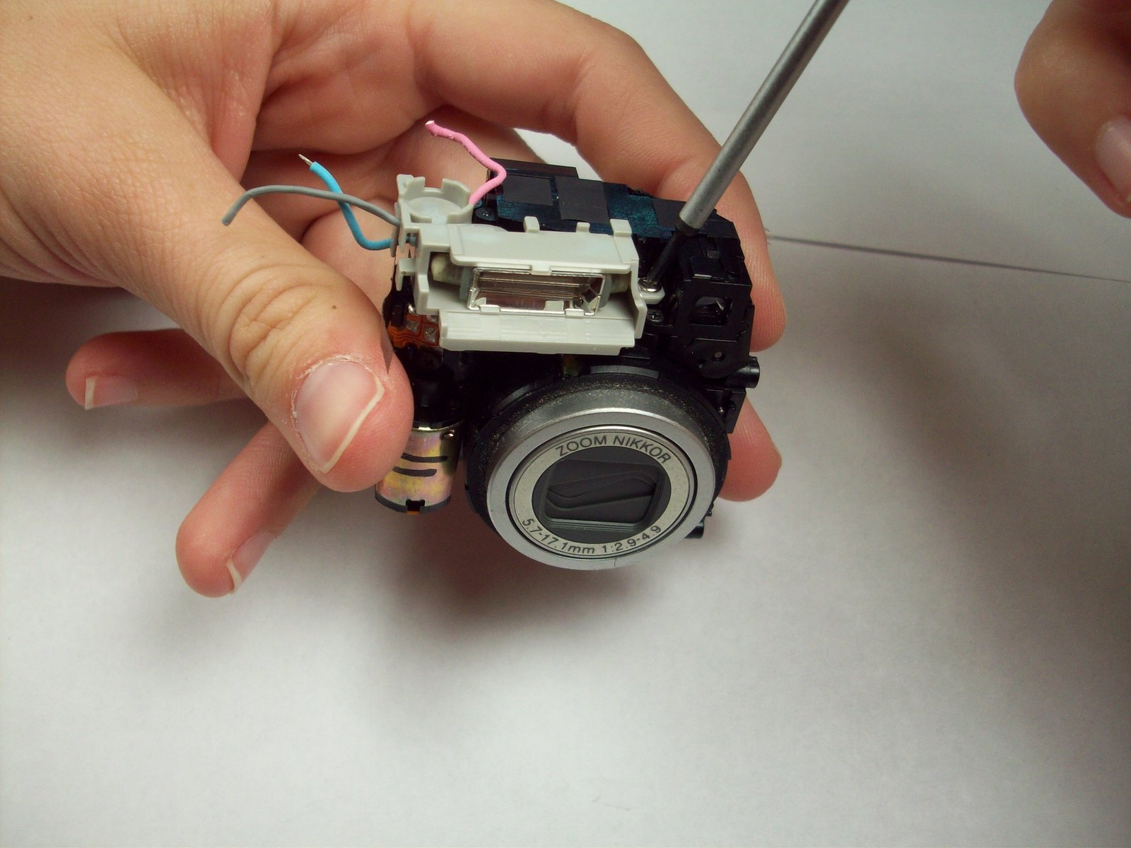Passo 11 Lens e Montagem do Flash O conjunto de flash e lente agora deve ser separada da placa-mãe. Localize o capacitor. É o componente que parece semelhante em tamanho e forma de uma pilha AAA.