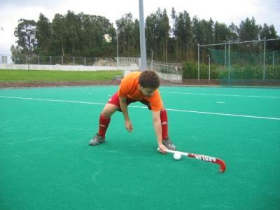 Receção de esquerda com uma mão Preparação: 1. Pega de mão esquerda; 2. O jogador deverá afastar as pernas à distância de um stick, mantendo-se em posição frontal em relação à trajetória da bola; 3.