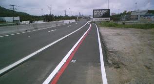 Ciclofaixas com tachões da SC-401 Infraestrutura: Ciclofaixa às margens da Rodovia estadual SC-401, com segregação do trânsito de veículos automotores feita apenas por tachões e pintura vermelha.