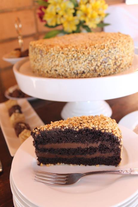 Bolo CHOCOLATE CAKE Três camadas de Bolo de Cacau (Callebaut) intercaladas com creme maltado de chocolate meio amargo e cobertas com creme e amendoim.