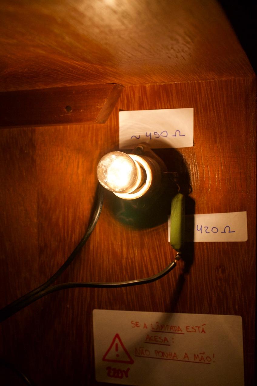 Hoje eu instalei essa lampadinha na estante do meu quarto: os fios estão ligados na tomada. A tensão da rede aqui em SC é 220 V. Eu medi as resistências da lâmpada e do resistor com o multímetro.