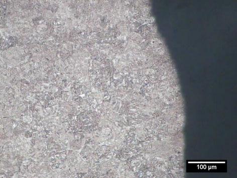A superfície de fratura é caracterizada frágil, com marcas radiais e a expansão lateral inferior a 10% indicando uma baixa ductilidade do material nesta condição.