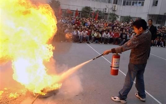 USO DOS EXTINTORES PORTÁTEIS NORMAS TÉCNICAS GERAIS Mantenha o extintor em pé, na POSIÇÃO VERTICAL; QUEBRE O LACRE E ACIONE O GATILHO; Dirija o jato para A BASE DAS CHAMAS e NÃO para o meio do fogo;