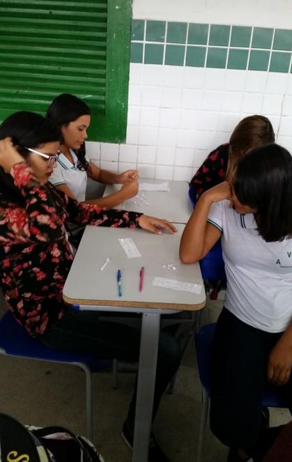 Sempre que esse bingo é realizado, os alunos se divertem e revisam o conteúdo ao mesmo tempo. Imagens: Professora chamando as bolas sorteadas e alunos marcando as cartelas.