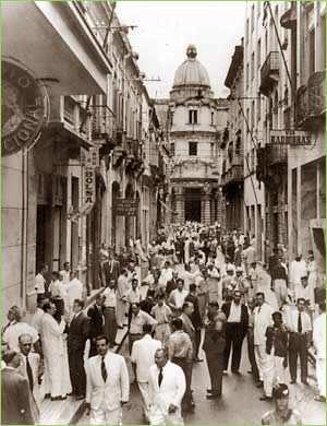 Figuras 2.22 e 2.23 - Rua XV de Novembro ao fundo a Bolsa de Café (1922), com movimento dos negócios do café, início do século XX. Fotos: acervo Boris Kauffmann e cartão postal da Cia.