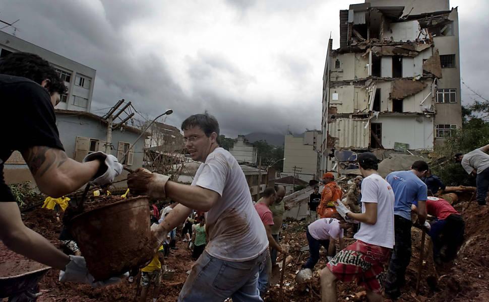 Tragédia no Rio de Janeiro: Mais uma vez, a culpa é da chuva? Voluntários retiram terra de prédio que desabou e soterrou moradores em Nova Friburgo (RJ).