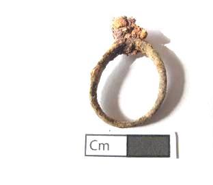 Tratase, segundo Kathleen Deagan, de um género comum dos anéis do século XVII, em que uma banda em cobre fundido simples e ligeiramente fina, com um quadrado saliente em bisel onde era colocada uma