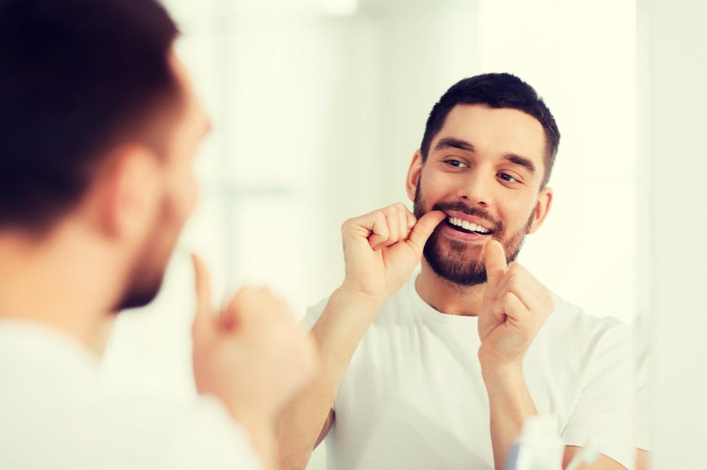 A maneira correta de usar o fio dental. O uso contínuo do fio dental elimina a placa acumulada entre os dentes e no início da gengiva.