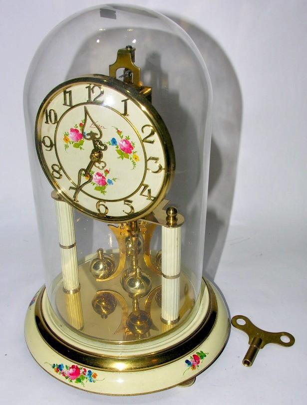(7) Como exemplo da aplicação do pêndulo de torção, existem alguns relógios de torção (figura ) que são, geralmente, cobertos com uma cápsula de vidro para que não sofra influência do meio externo.