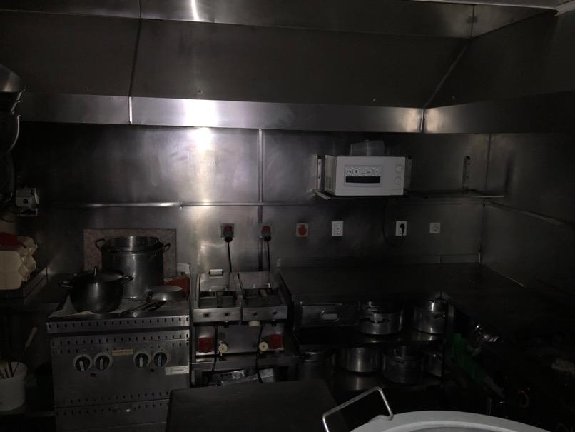 porta, uma bancada em inox com três gavetas, um sistema de exaustão em inox, uma bancada com lava loiça em inox retangular com cerca de