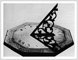 2ª Questão: Os relógios de sol podem ter em seu centro um pino ou uma placa com formato parecido com o de um triângulo, como o da figura a seguir. Sua sombra sobre o mostrador indica a hora do dia.