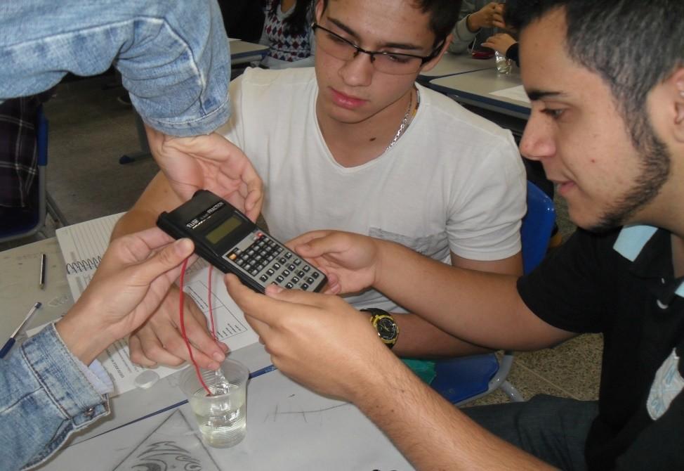 Figura 3: bolsista ID auxiliando os alunos da turma 302 do 3º ano do ensino médio, na montagem em calculadoras, utilizado para teste energético do experimento.