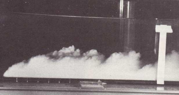 Figura 12: Corrente turbidítica experimental em um condutor no Caltech. A profundidade da água é de 28cm. Note a forma característica da cabeça da corrente e os redemoinhos atrás dela.