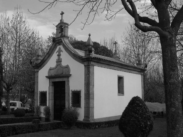 Fachada orientada a norte, com porta principal de moldura de pedra e frontão curvo, volutas na base e rematada por flor de liz. A porta é ladeada por duas janelas.