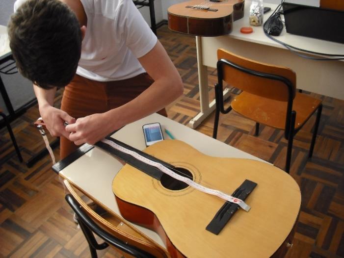 Figura 12 Alunos marcando a posição de todos os trastes do violão Os alunos utilizaram um aplicativo disponível gratuitamente na internet que determina a frequência sonora de cada uma