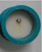 27 - Cilindro de borracha com um conjunto dente/braquete incluso em resina acrílica, formando um corpo de prova.