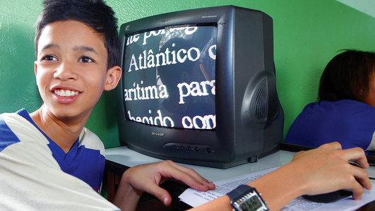 Kevin Vitor Neri Nunes, aluno que usa uma lupa eletrônica para ampliar o texto. O Kevin é aluno regular na EM Bento Machado Ribeiro.
