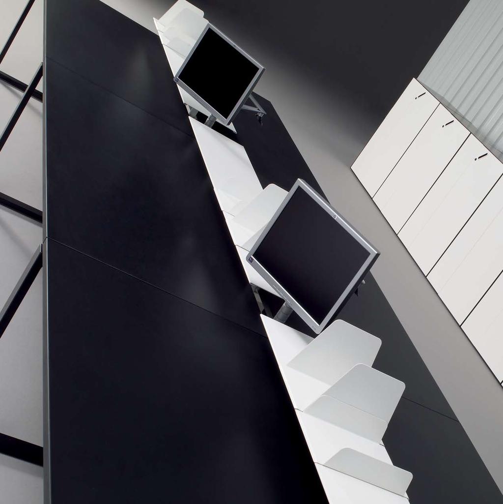 18 19 Área de trabalho dupla (1600mm) perna O em preto, o segundo nível central com prateleiras em branco, suportes de monitor totalmente reguláveis e tampos em preto.