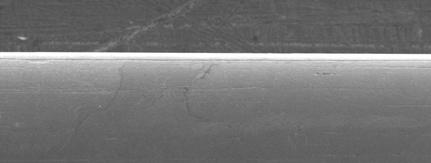 A avaliação da superfície lateral do fio superelástico em NaClO 1% (Figura 42) sob MEV revelou ranhuras e trincas no eixo