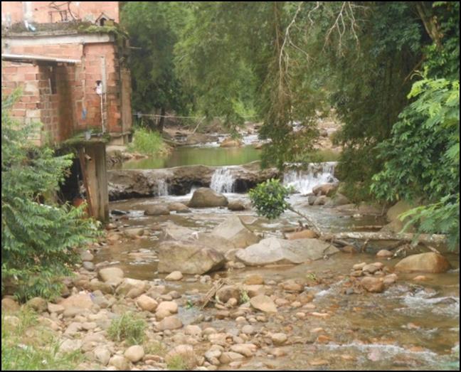 Figura 6: vista geral do curso do trecho do Rio Soberbo em Guapimirim. Observar a fundação das casas diretamente assentadas em material heterogêneo e instável.