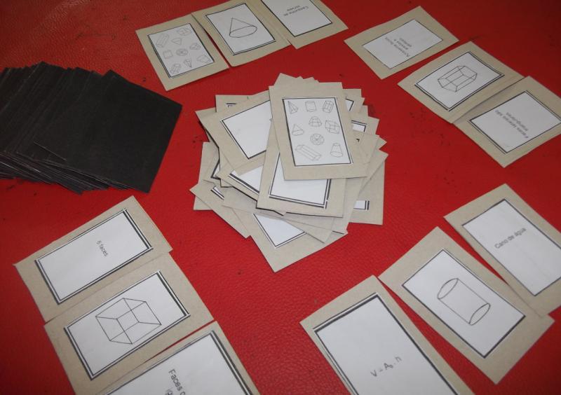 O jogo Piff Geométrico possui o total de 108 cartas, sendo 4 coringas, 18 cartas com o desenho de sólidos geométricos (carta figura) (fig.